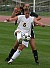 Amy Larson kicks the ball with a Pioneer breathing down her neck.