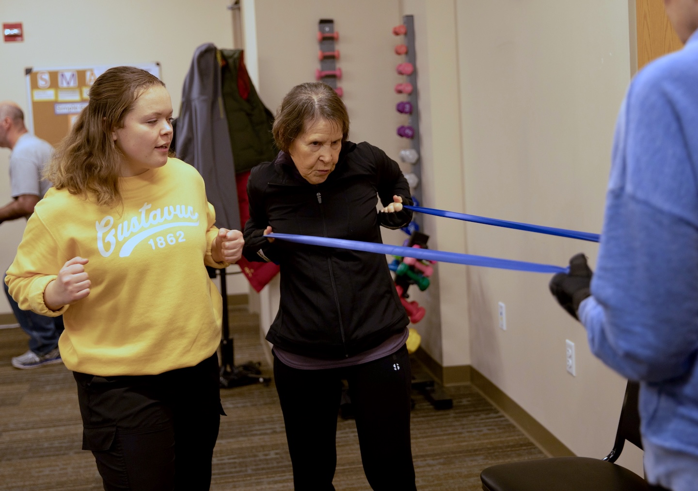 A young woman helps a client use resistance bands.